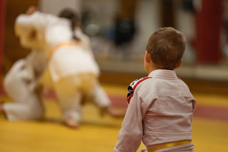 Ein Kind im Judoanzug schaut beim Training zu